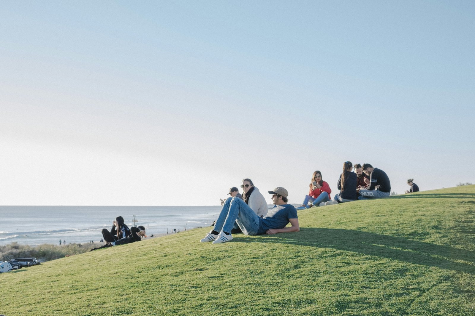 Young people relaxing on a grassy hill by the sea in Western Australia